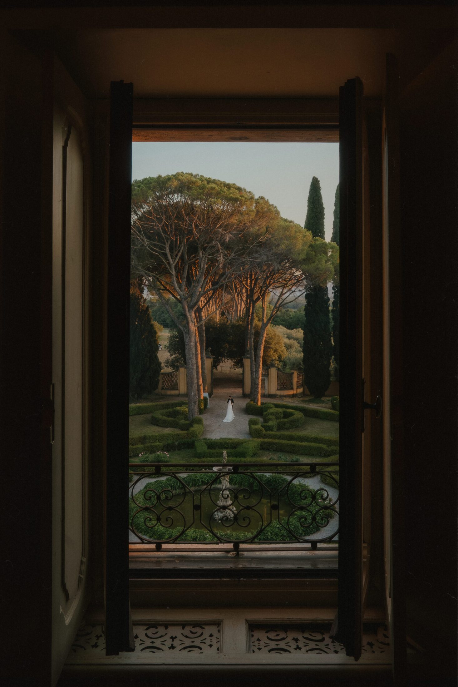 Sve što treba da znate o editorial wedding fotografiji 7 Fotografija mlade i mladoženje u parku, uslikana kroz prozor vile u Italiji.