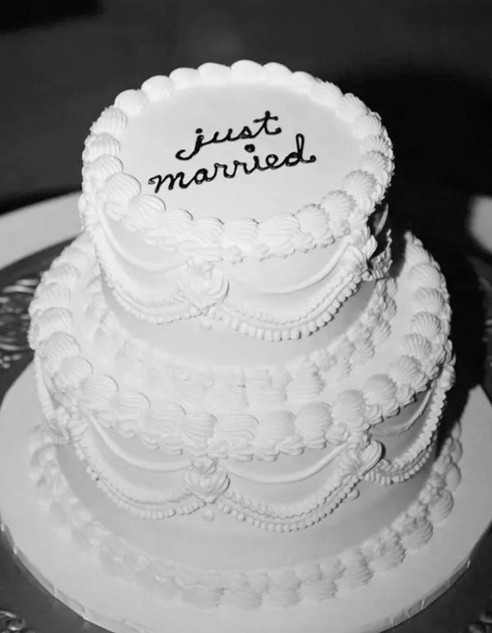 7 Wedding Cake Trends for 2025: Inspiring Designs for Modern Couples 15 White two-tier vintage-style wedding cake with 'just married' spelled on top.