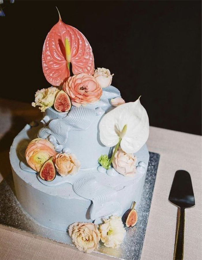 7 Wedding Cake Trends for 2025: Inspiring Designs for Modern Couples 10 Blue two-tier wedding cake with colorful fresh flower details.