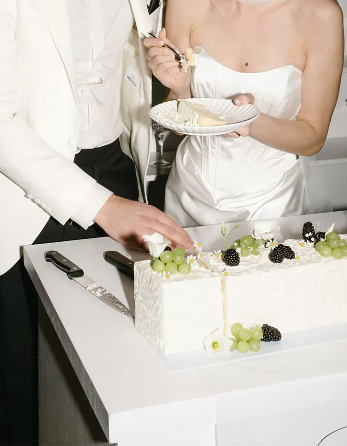 7 Wedding Cake Trends for 2025: Inspiring Designs for Modern Couples 9 Editorial-style photo of a bride and groom cutting a white sheet cake on their wedding day.
