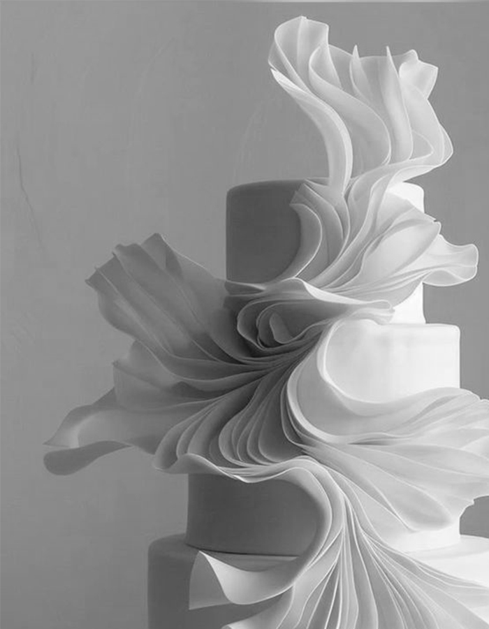 7 Wedding Cake Trends for 2025: Inspiring Designs for Modern Couples 5 White wedding cake with fondant sculptural draping, captured in an editorial-style in black and white