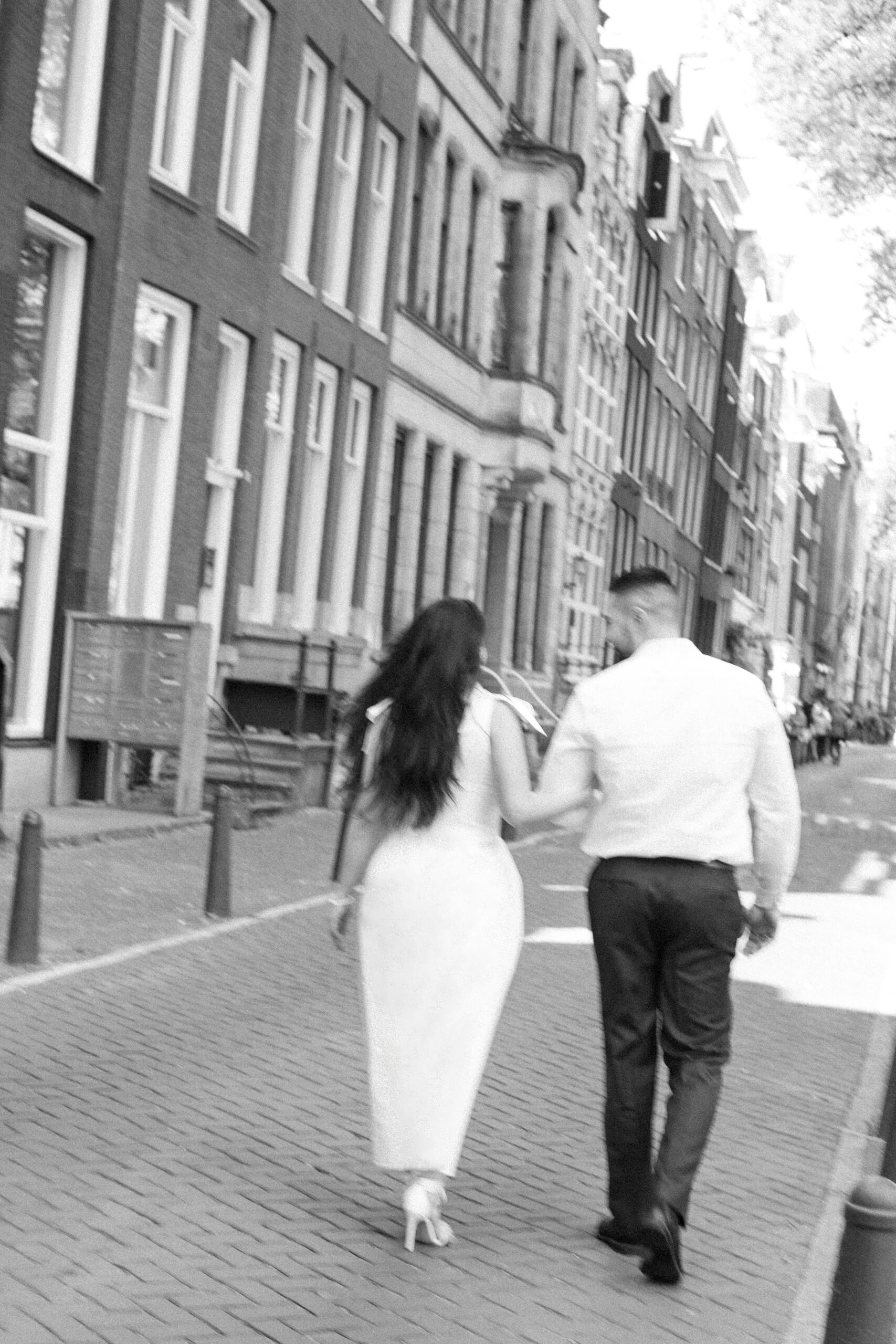 Planning a Surprise Proposal? Hire an Engagement Photographer in Amsterdam 11 Couple walking near famous canal houses in Amsterdam after getting engaged