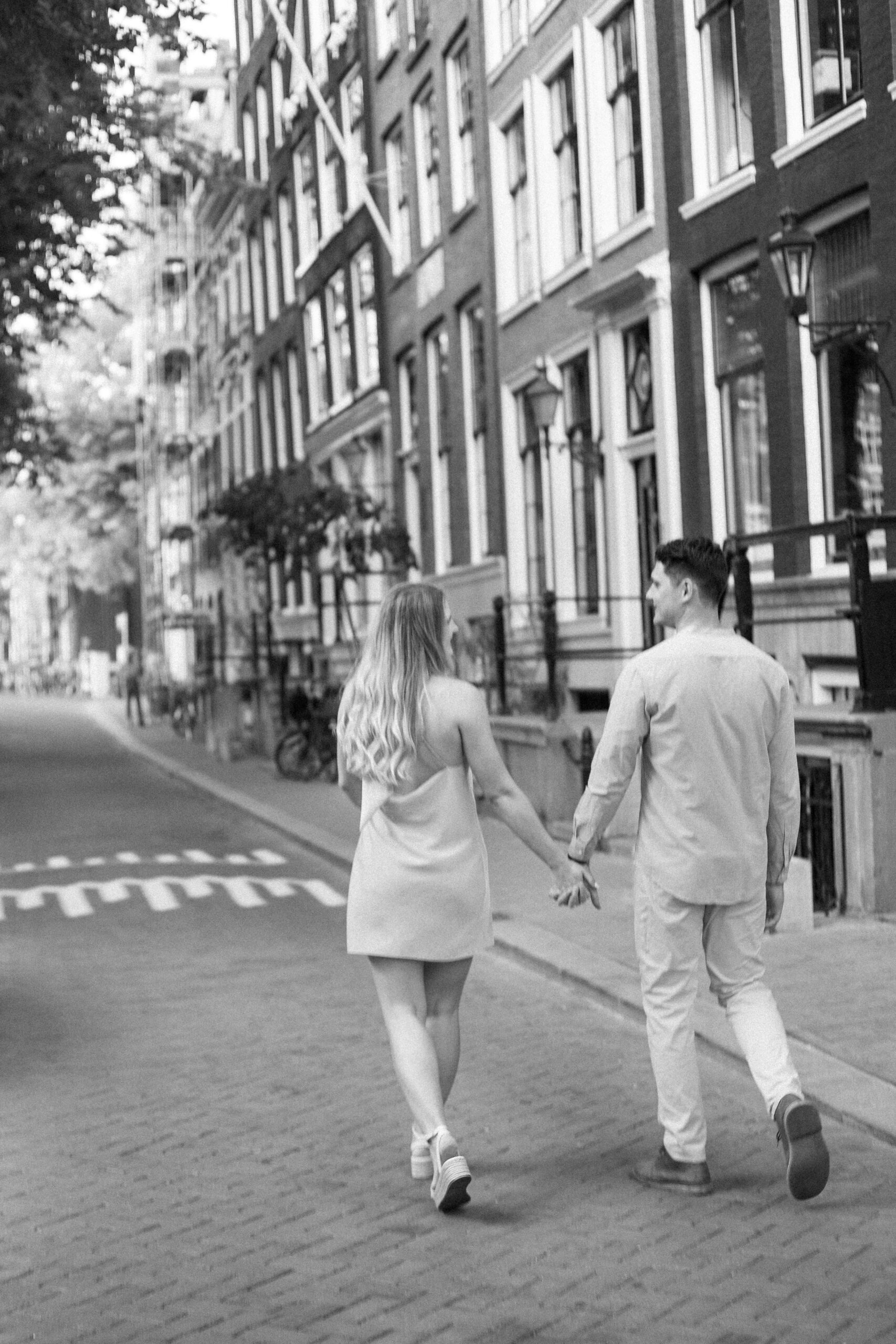 Couple Photoshoot in Amsterdam: A Romantic Escape Captured in Editorial Style 11 Couple walking near famous canal houses in Amsterdam