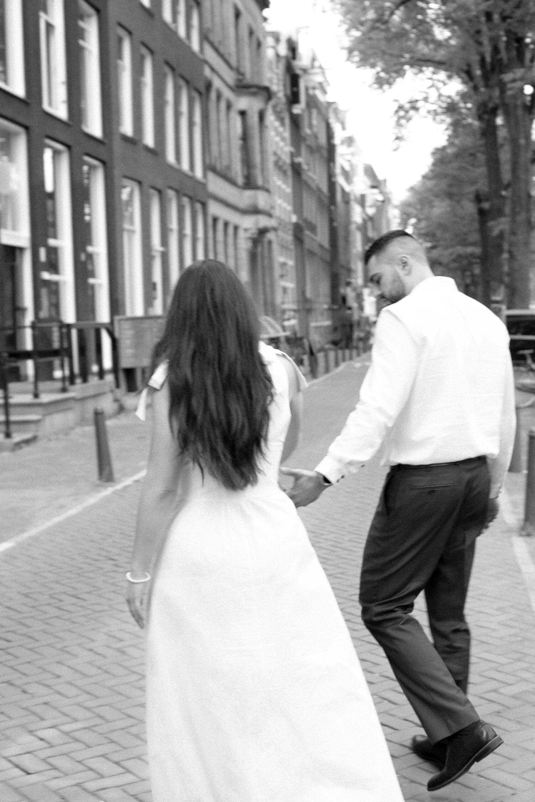 Couple walking near famous canal houses in Amsterdam after eloping