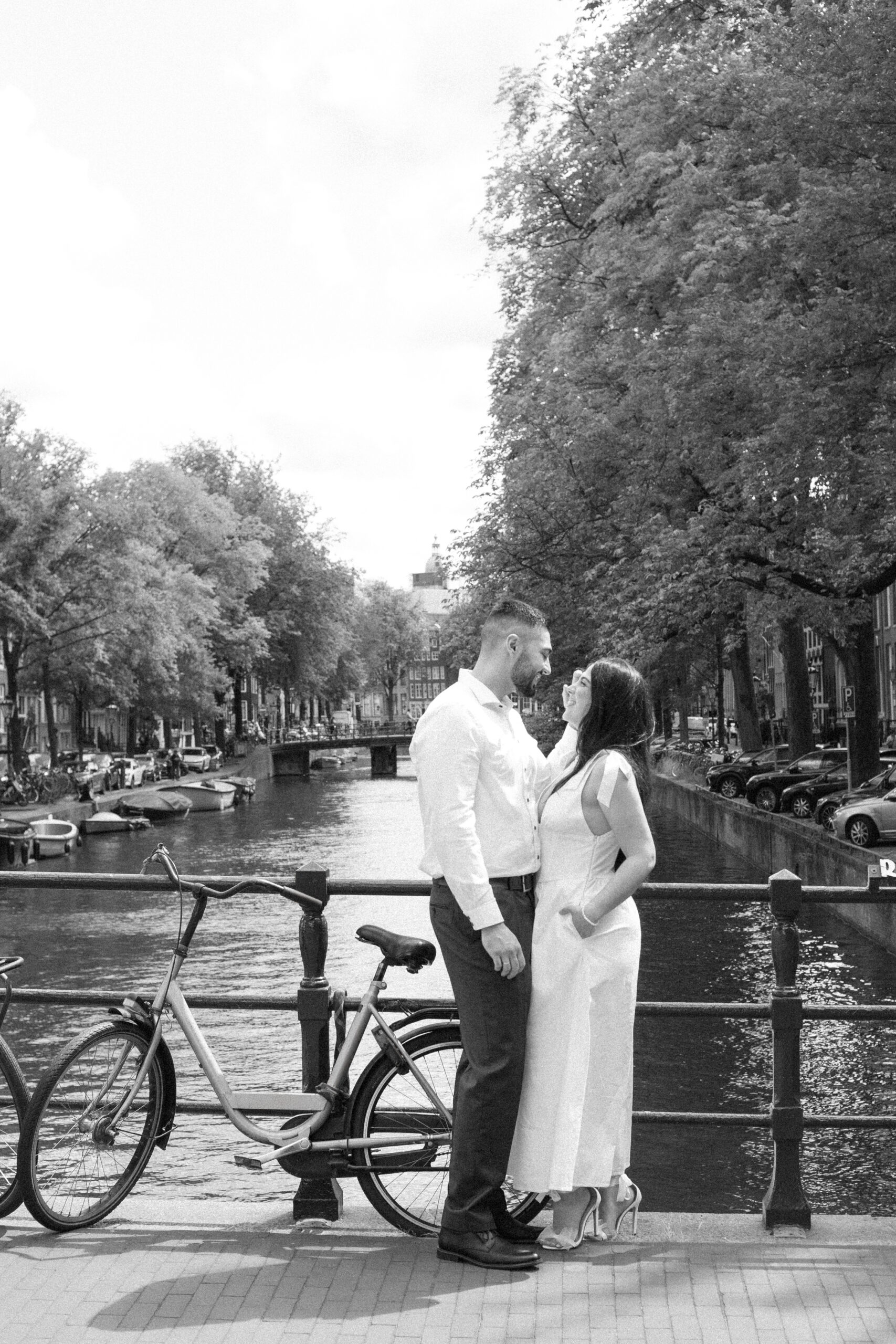 Black and white photo of a bride and groom standing on a bridge over a canal in Amsterdam