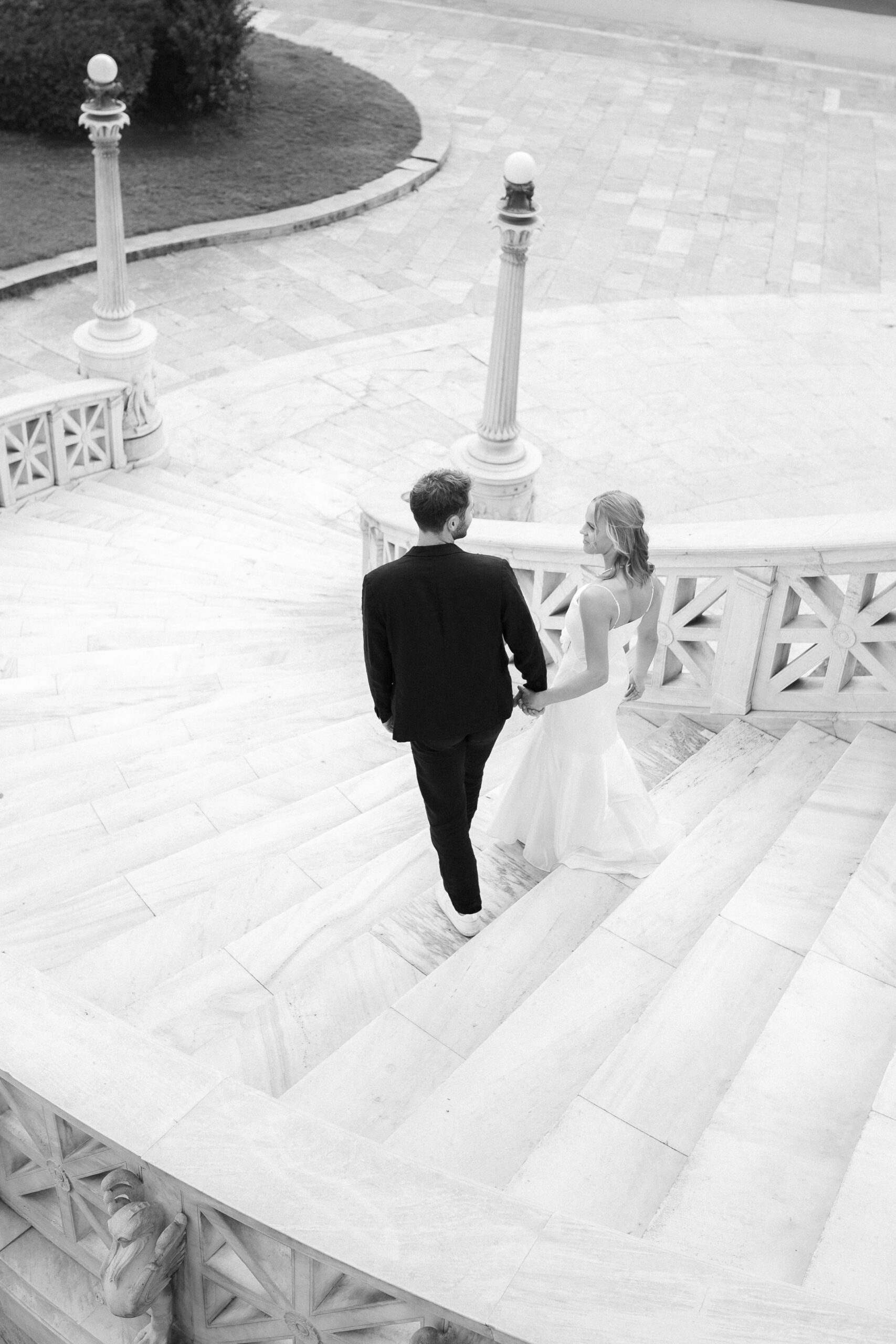 Editorial style photo of bride and groom walking, captured in front of the Athens National Library in Greece