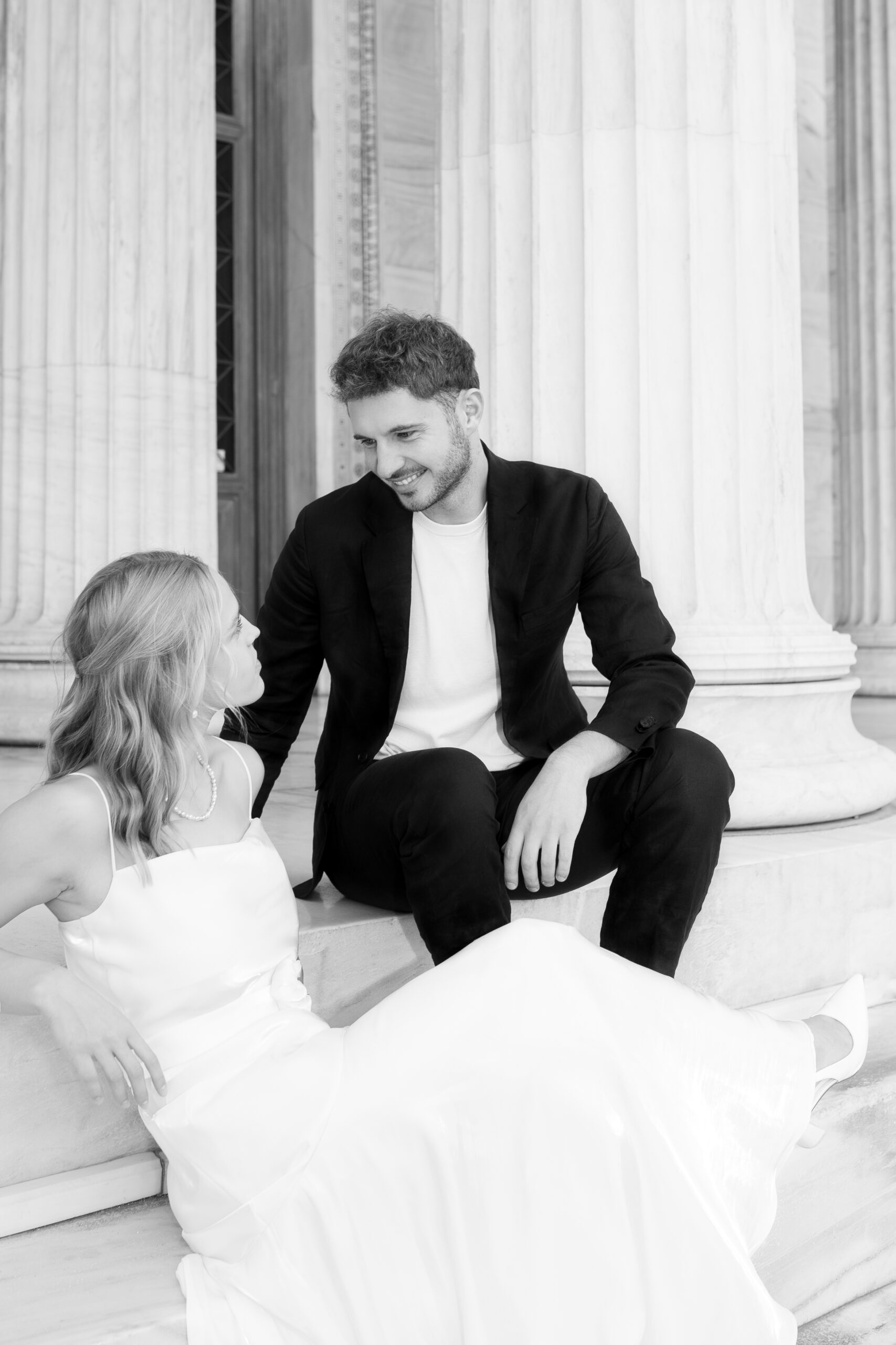 Loose editorial shot of bride and groom sitting and talking, captured by a destination wedding photographer in Athens, Greece