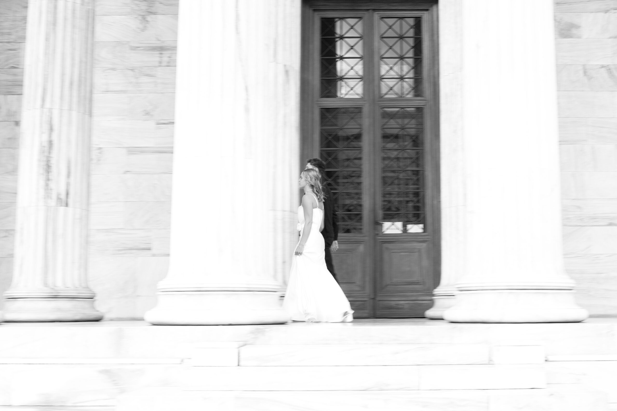 Athens Post-Wedding photoshoot - bride and groom captured walking, photographed in loose editorial style in front of the National Academy of Athens