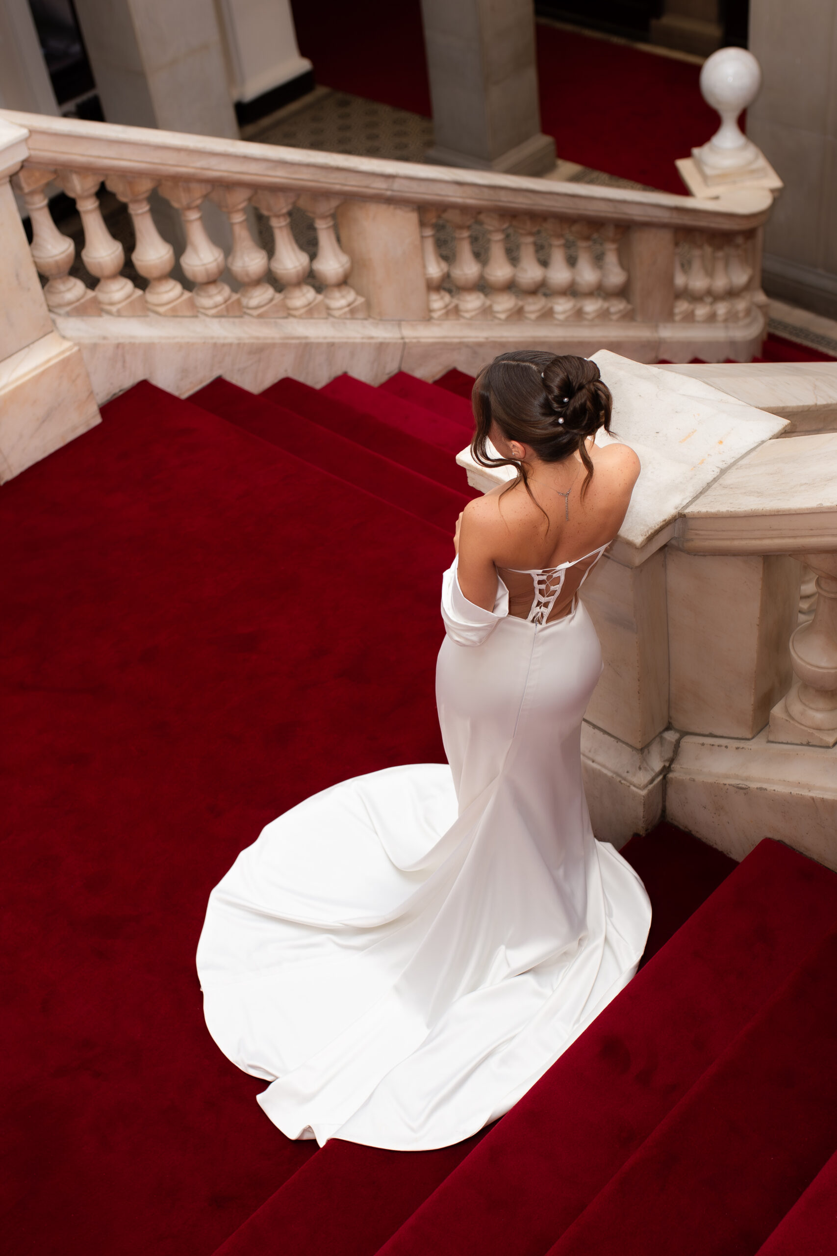 Beautiful, editorial style photo of the bride in a backless wedding dress, standing on the grand staircase of a European villa on her wedding day