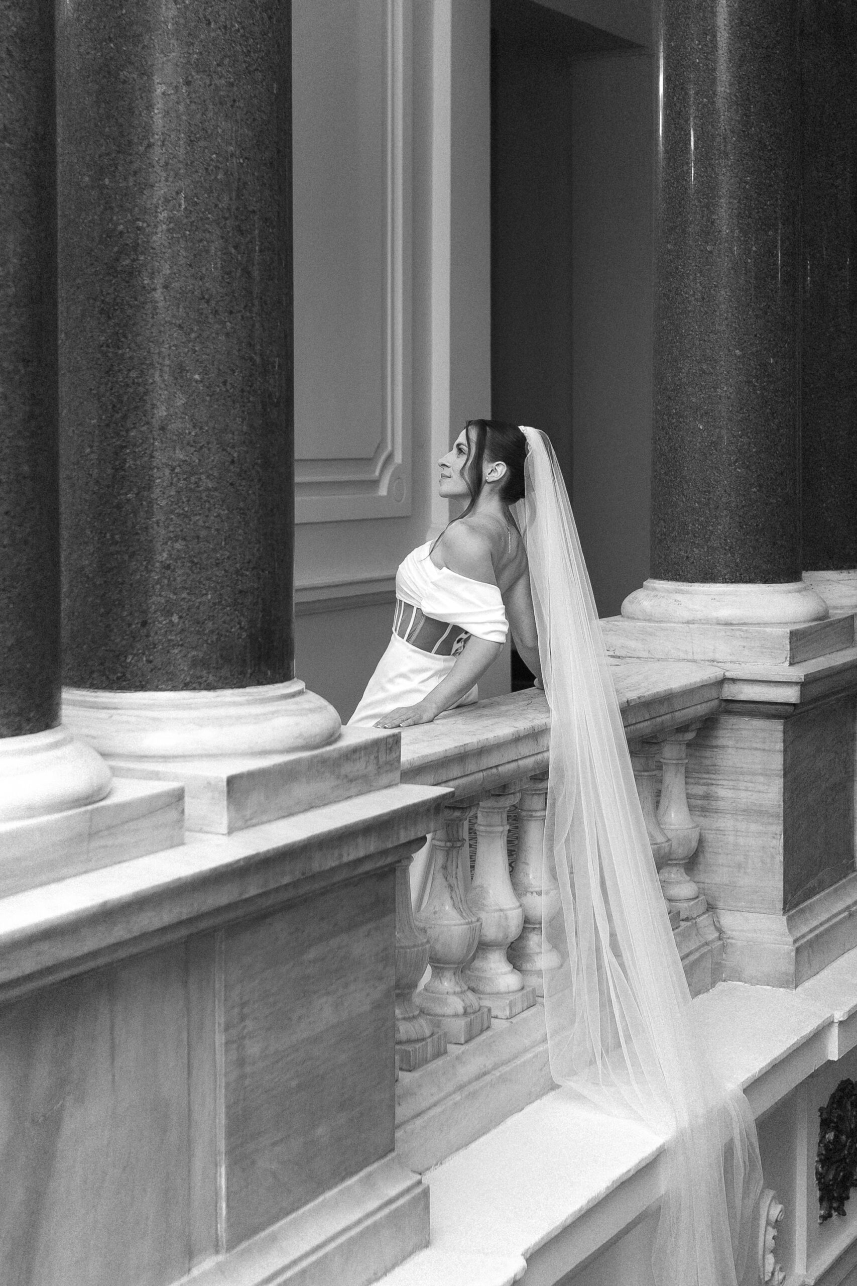 Photo of the bride leaning against the railing with her veil gently falling behind her