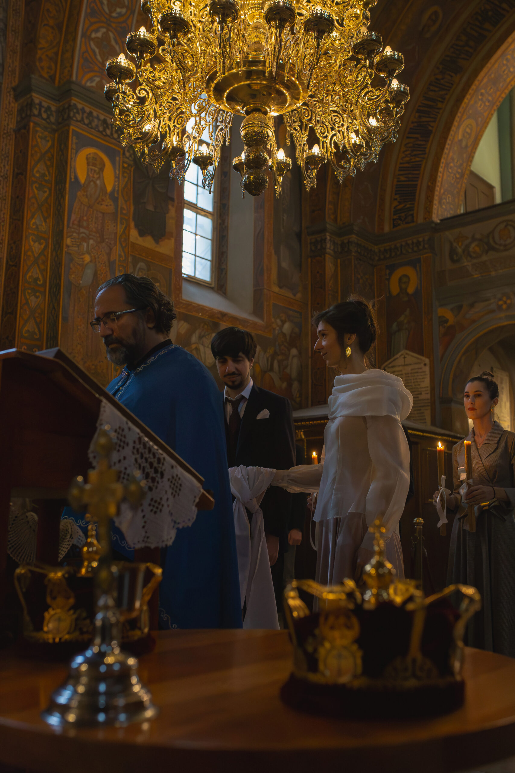 Mlada i mladoženja tokom čitanja molitvi na crkvenom venčanju u Vaznesenjskoj crkvi u Beogradu, bogato oslikan enterijer crkve