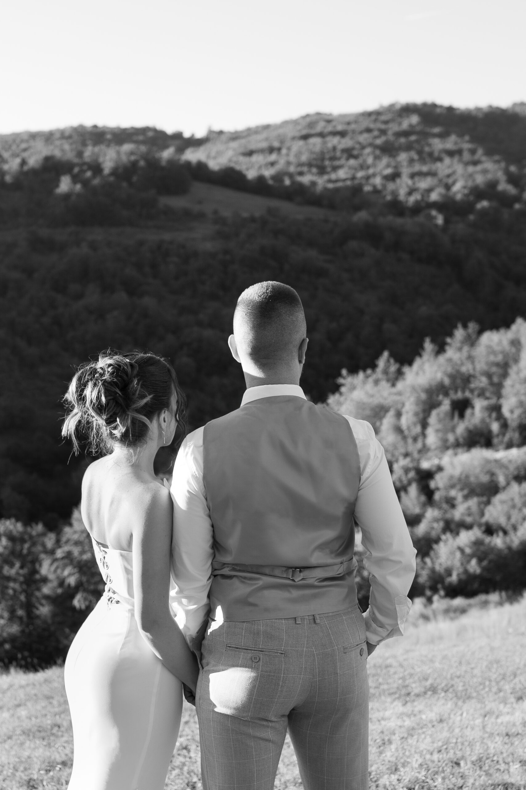 Romantična crno-bela fotografija mladenaca na Kosmaju sa pogledom na šumu i brda