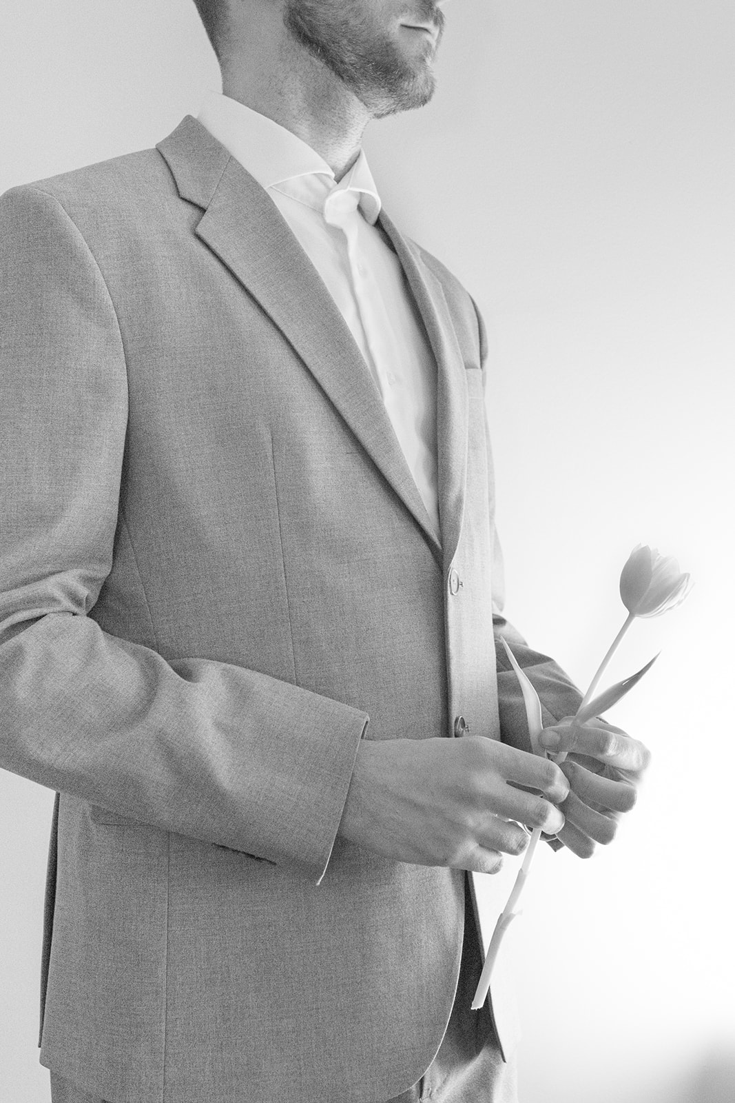 groom holding a tulip flower, romantic black and white photo