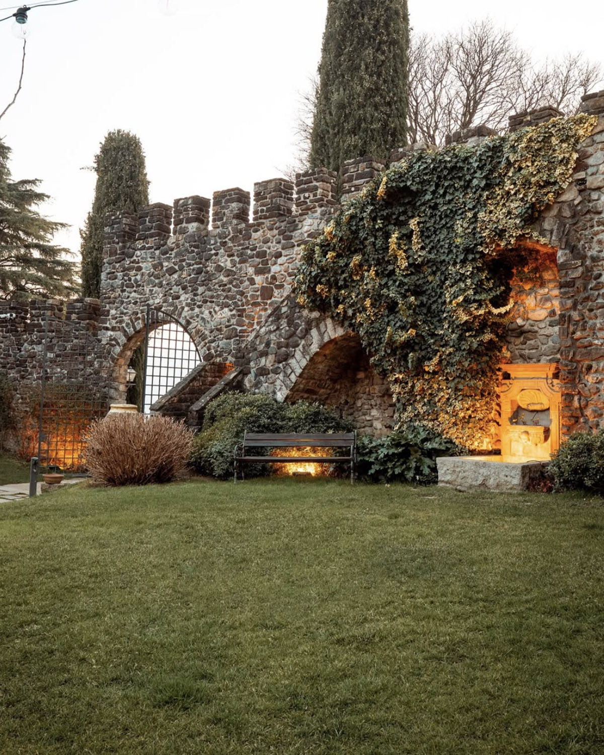 Bergamo, Italy – stone castle courtyard with ivy-covered arches and warm evening lights creating an intimate, editorial wedding atmosphere.