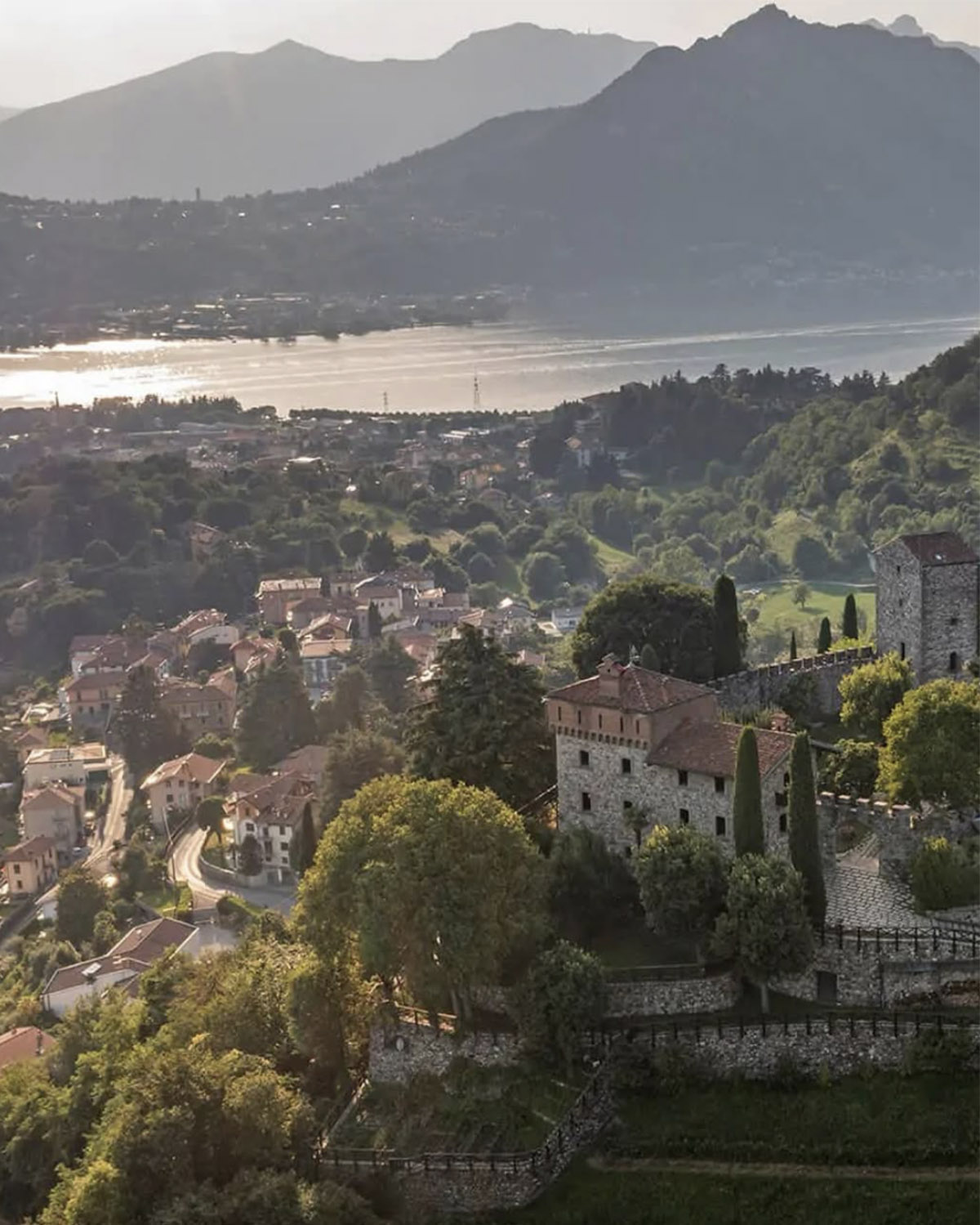 Lake Como near Bergamo – panoramic view of a historic castle overlooking the lake and mountains, captured in soft, romantic editorial light.