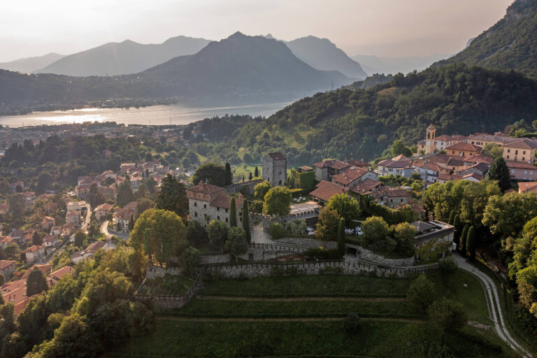 Castello di Rossino, Bergamo – wide landscape view of the castle venue above the lake with mountains in the background, photographed in a timeless editorial style.