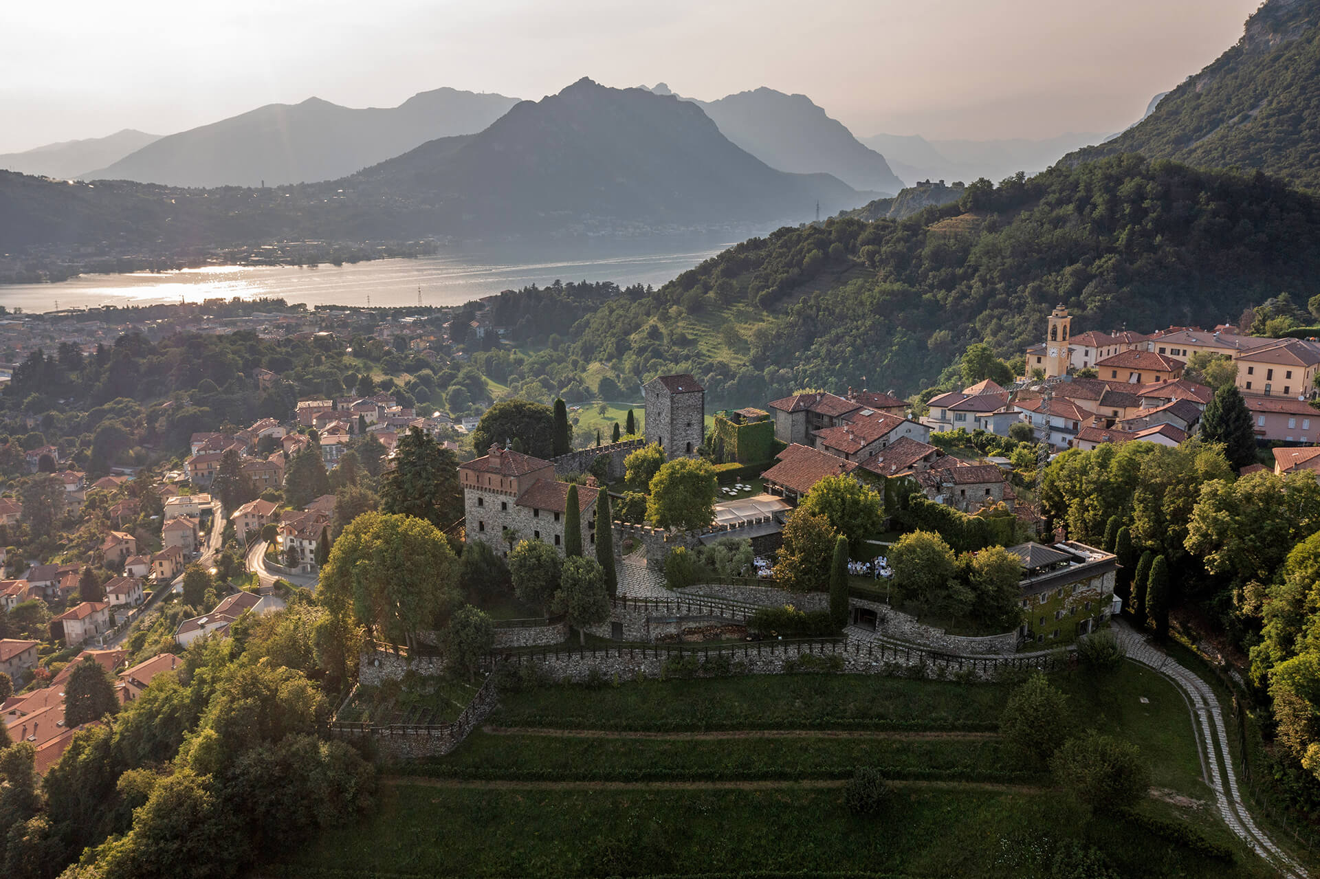 Castello di Rossino, Bergamo – wide landscape view of the castle venue above the lake with mountains in the background, photographed in a timeless editorial style.
