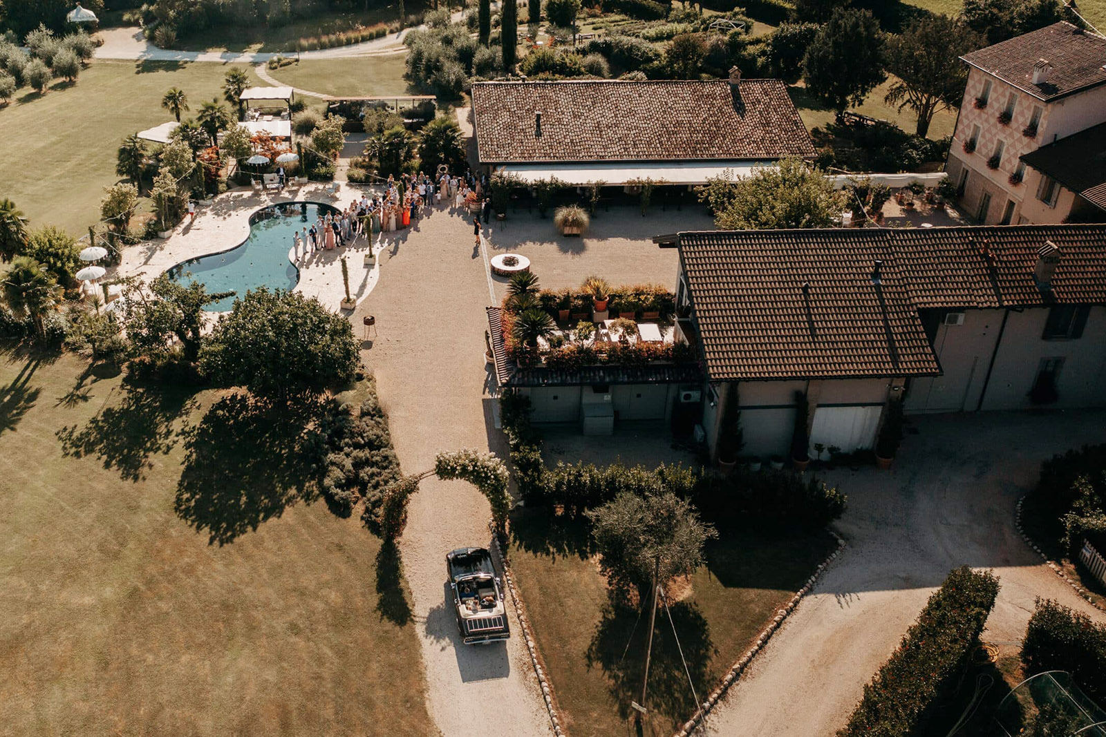 Tenuta Serradesca, Bergamo – aerial view of the wedding venue with pool, gardens, and arriving guests, presented in a warm, editorial perspective.