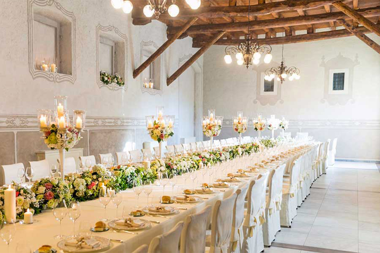 Bergamo, Italy elegant reception hall with a long candlelit banquet table adorned with florals, styled in a bright, airy editorial wedding aesthetic.