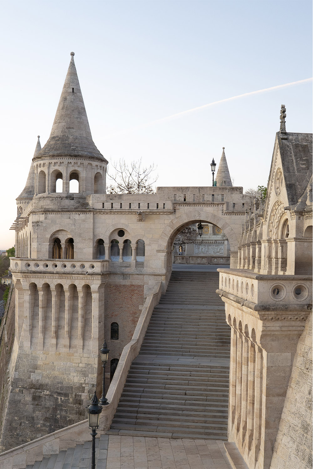 At Fisherman’s Bastion in Budapest, ornate stone towers and sweeping staircases are shown in warm morning light, photographed in a clean, architectural editorial style.