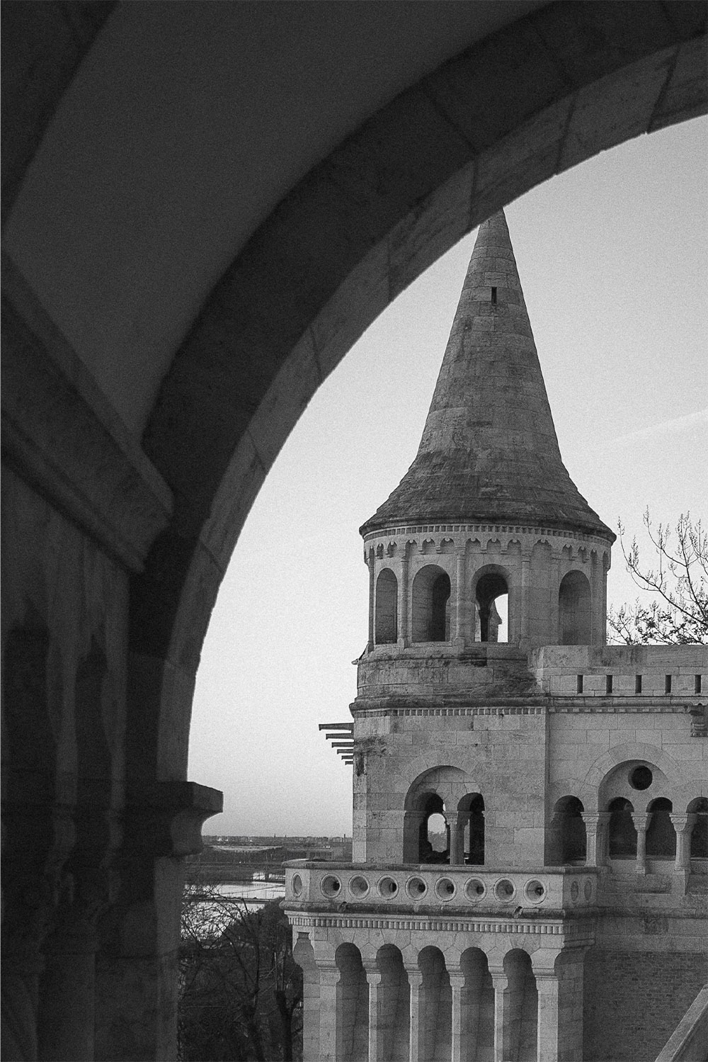 At Fisherman’s Bastion in Budapest, a dramatic close-up of a turret framed by curved stone arches is captured in moody black-and-white, emphasizing texture in an editorial style.
