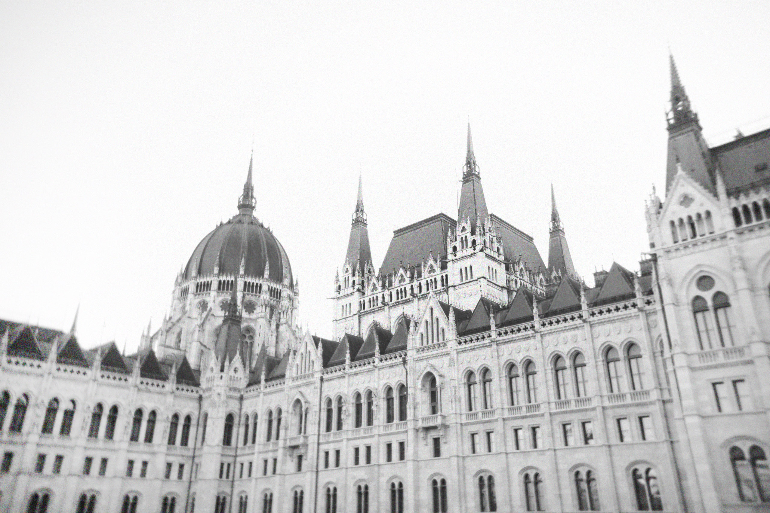 t the Hungarian Parliament Building in Budapest, the grand façade with domes and spires is captured in a slightly blurred black-and-white frame, styled as a cinematic editorial image.