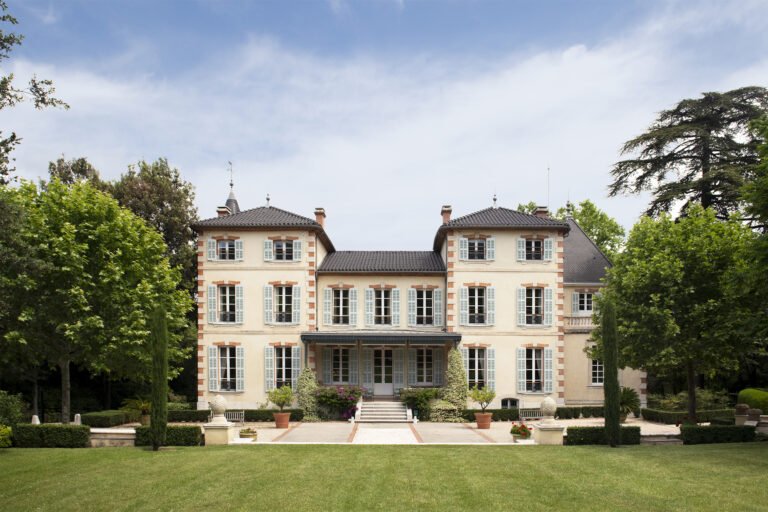 A symmetrical front view of Château de Forbin in Provence, France, with its classic shutters and landscaped grounds presented in a clean, timeless editorial style.