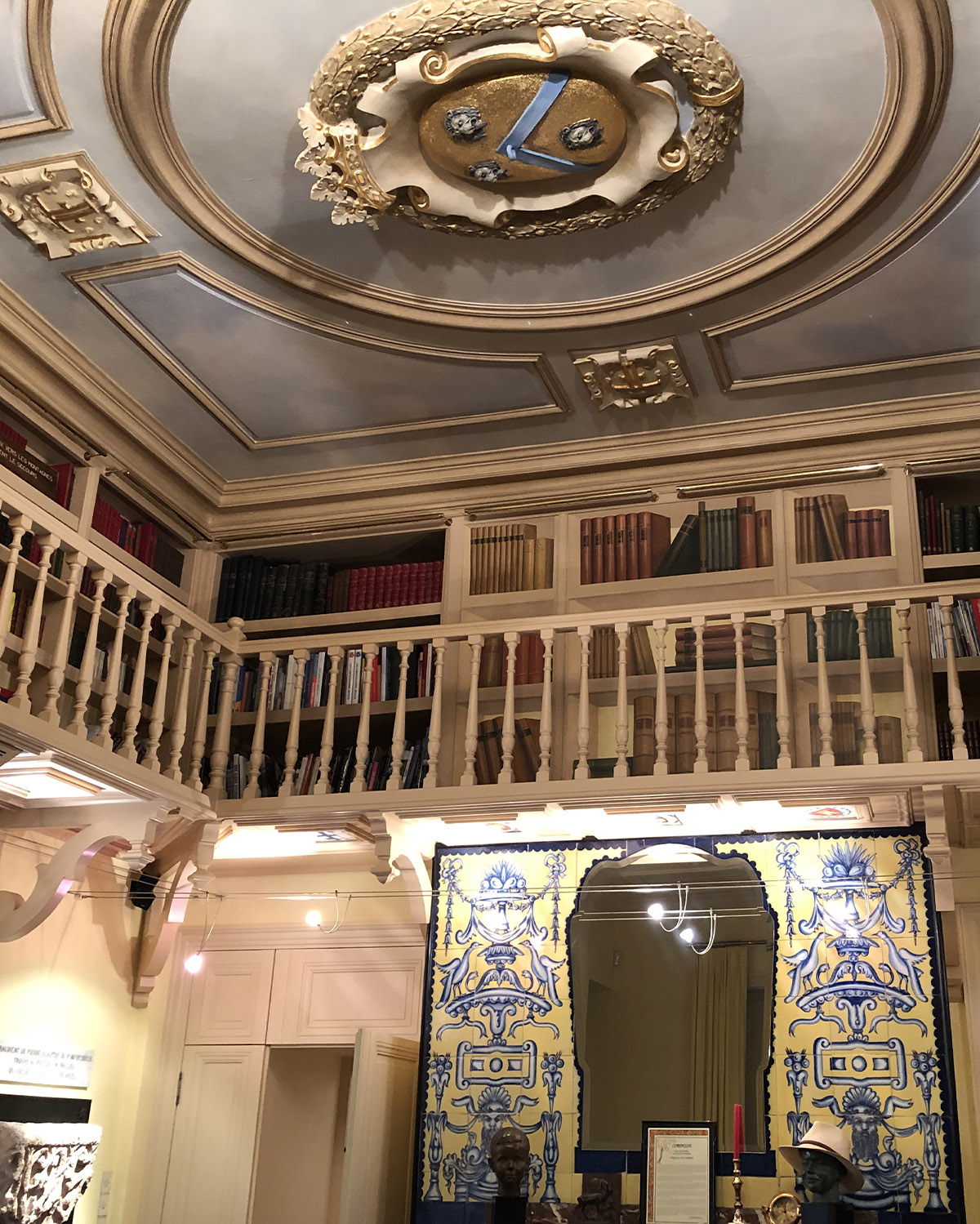 Inside Château de Forbin in Provence, France, an ornate library with a mezzanine of bookshelves, decorative ceiling details, and warm lighting is captured in an intimate editorial style.