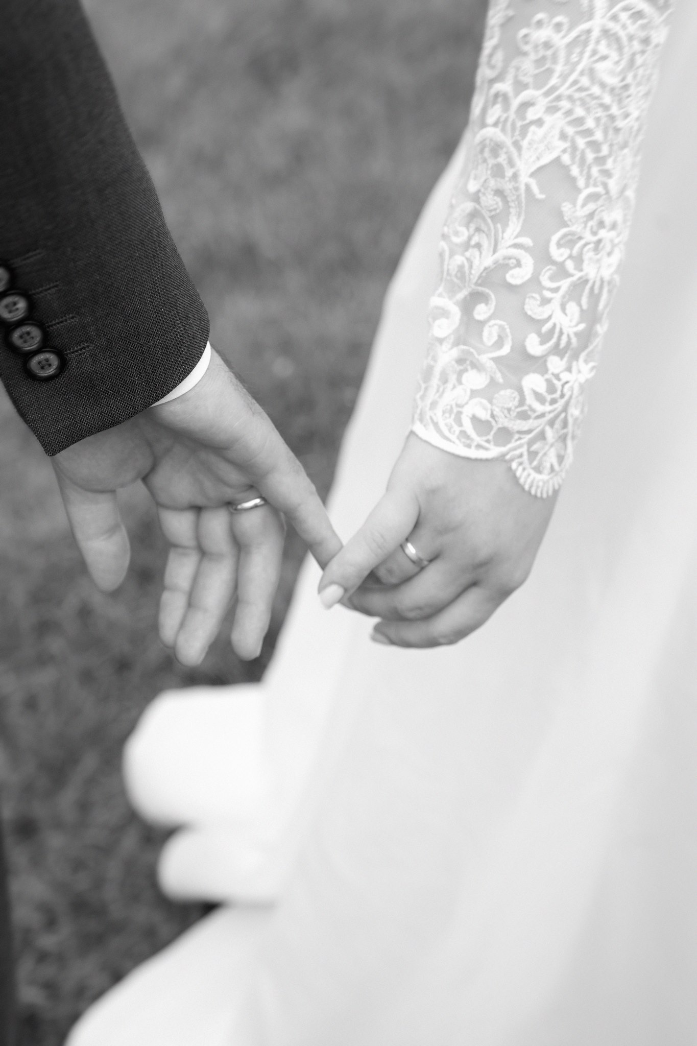 Belgrade Botanical Garden greenhouse grounds, a close-up of a bride and groom’s hands gently touching with wedding bands visible, captured in an intimate black-and-white editorial detail style.