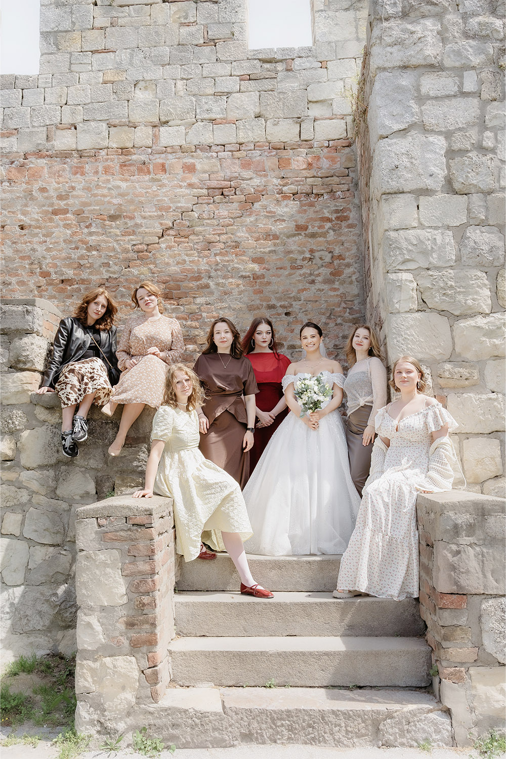 At Kalemegdan Fortress in Belgrade, the bride poses with her bridesmaids on historic stone steps in a stylish editorial wedding group portrait.