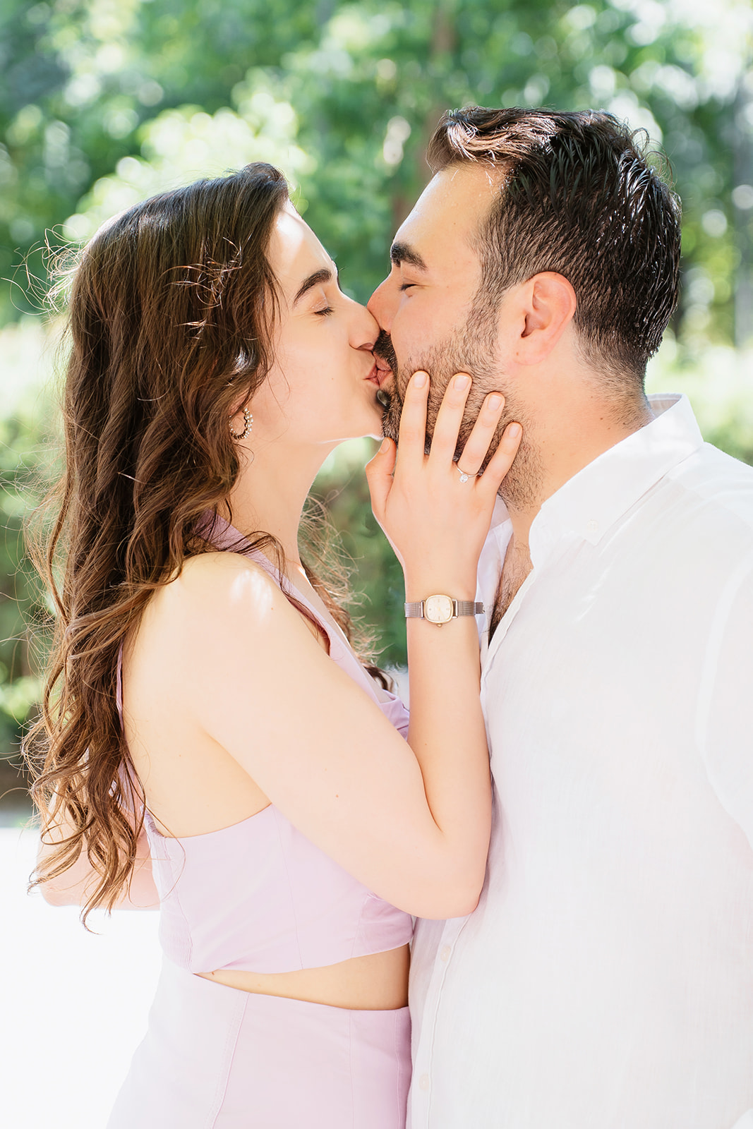 Editorial close-up engagement portrait of a couple sharing a kiss in a green park in central Belgrade with soft natural light.