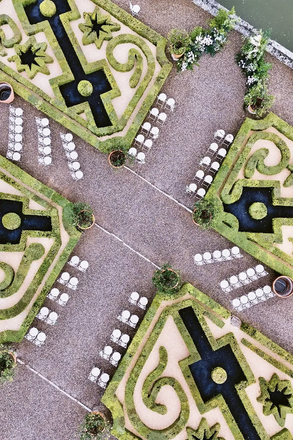 An editorial aerial photograph of the formal gardens at Castello di Celsa in Tuscany, Italy, arranged for an elegant outdoor wedding ceremony.