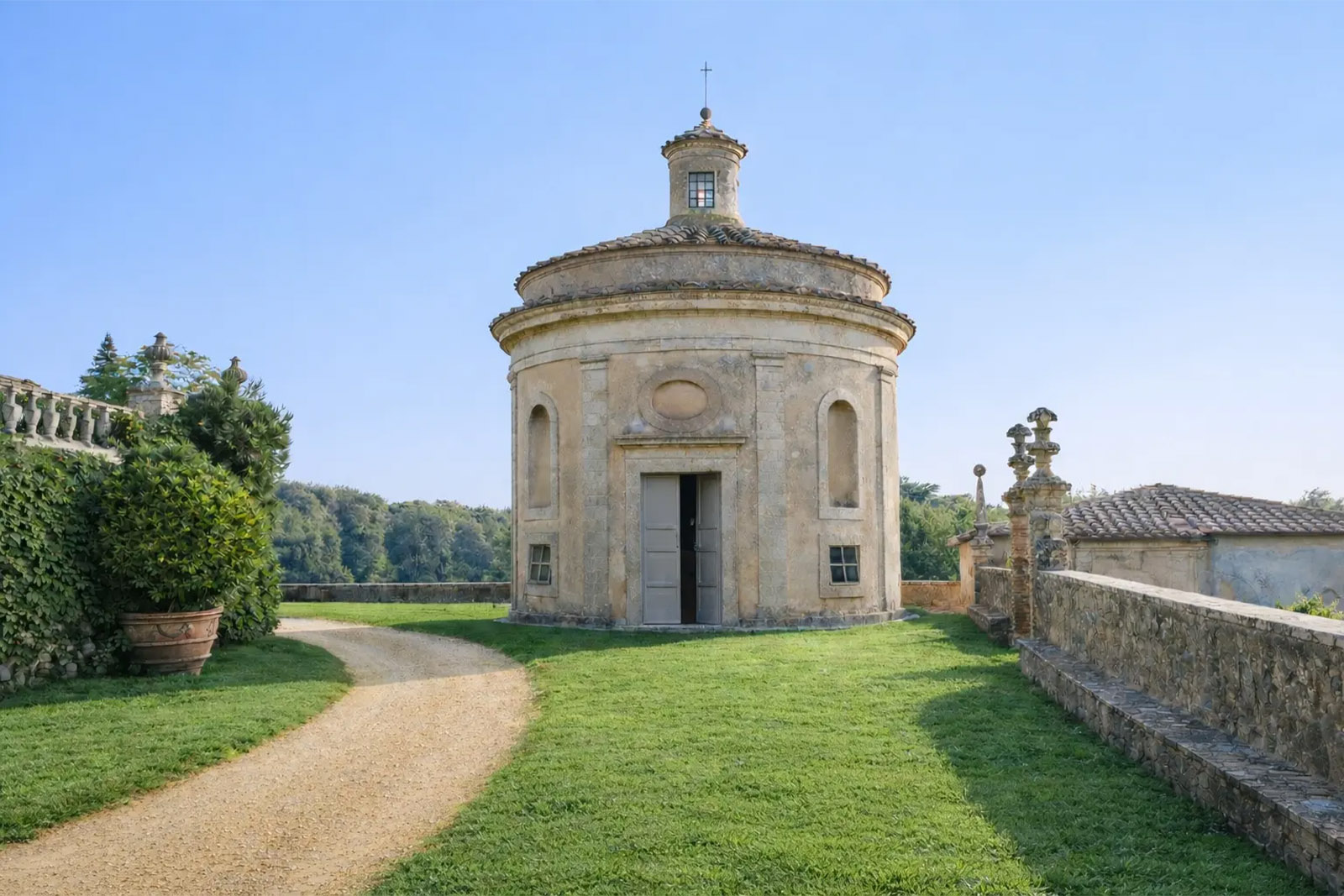 An editorial photograph of the historic chapel at Castello di Celsa in Tuscany, Italy, surrounded by lush lawns and peaceful gardens.