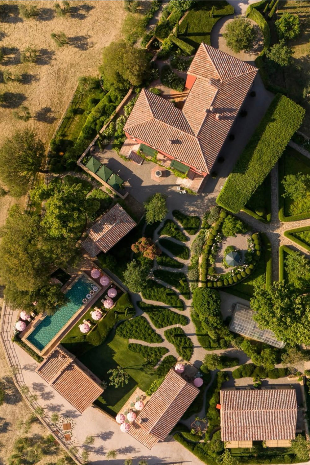 Casa Newton, Tuscany, Italy — an aerial view of the historic villa surrounded by manicured gardens, cypress trees, and rolling countryside, photographed in an editorial style.