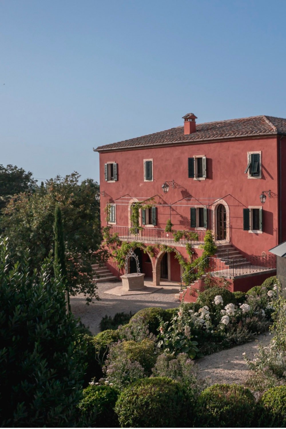 Casa Newton, Tuscany, Italy — the villa’s distinctive terracotta façade surrounded by Mediterranean gardens and stone terraces, photographed in a timeless editorial style.