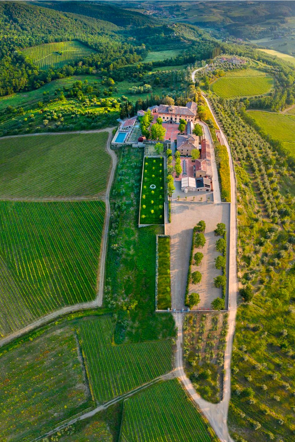 Il Borgo di Vignamaggio, Tuscany, Italy — An aerial view of Il Borgo di Vignamaggio surrounded by rolling vineyards and lush Tuscan countryside, captured in a refined editorial style.