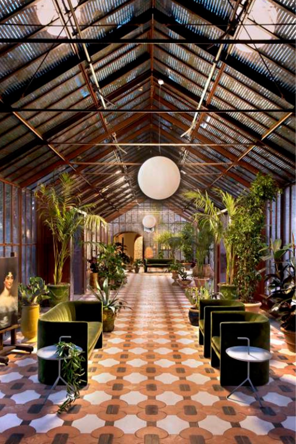 Il Borgo di Vignamaggio, Tuscany, Italy — The atmospheric glasshouse interior at Il Borgo di Vignamaggio, filled with tropical plants, patterned tiles and contemporary seating, photographed in an eclectic editorial style.