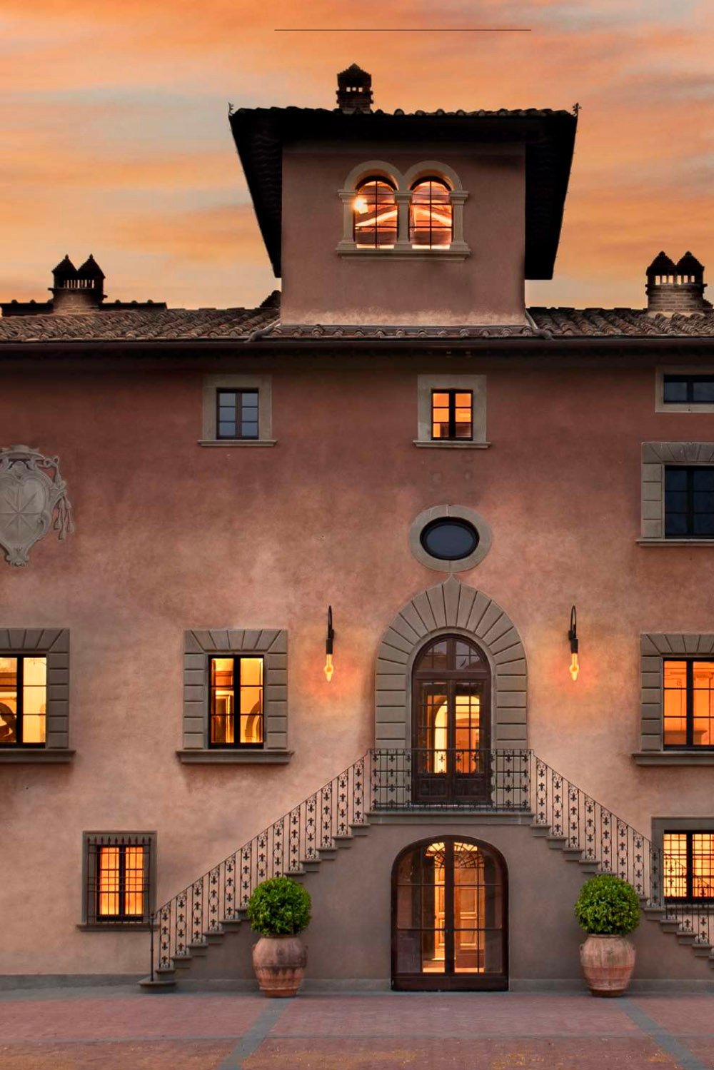 Il Borgo di Vignamaggio, Tuscany, Italy — The historic terracotta façade of Il Borgo di Vignamaggio glowing at sunset, with arched windows and stone details creating a warm editorial wedding setting.