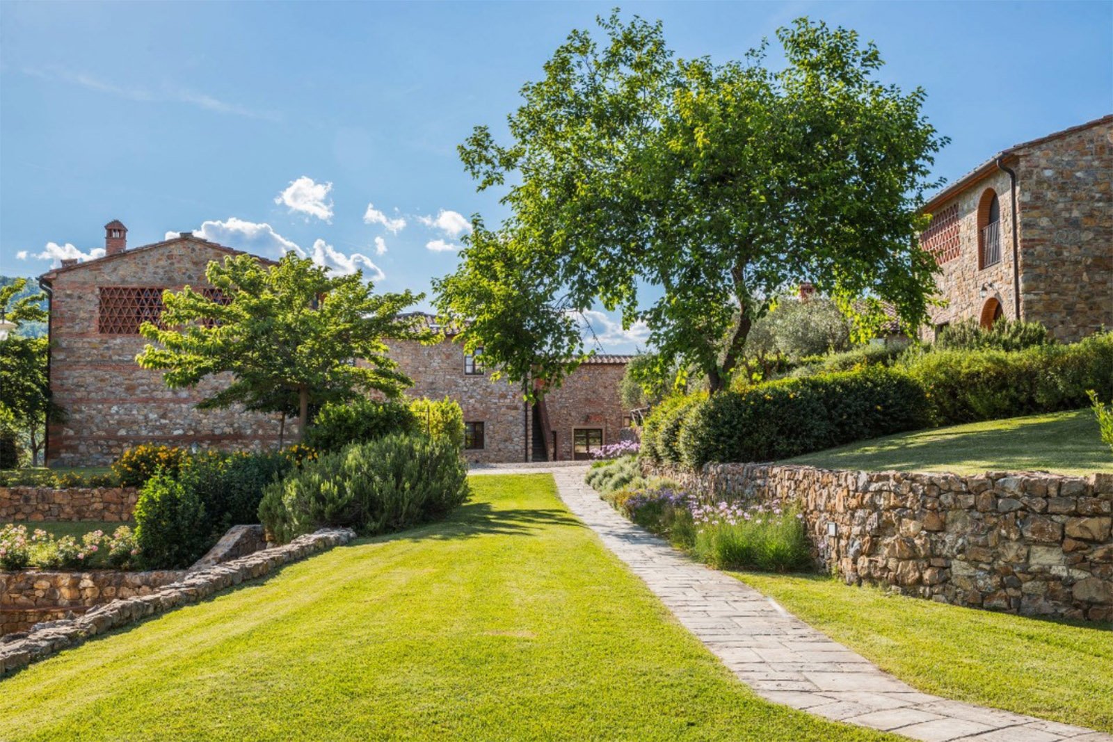Poggio Cennina Resort wedding venue: The stone buildings and manicured gardens of Poggio Cennina Resort in Tuscany, Italy, photographed in a bright and refined editorial style.