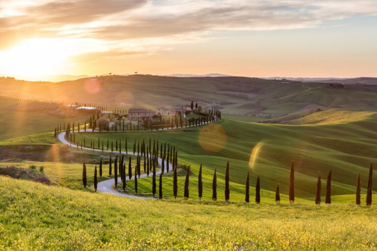 9 Underrated Wedding Venues in Tuscany | Italy Destination Wedding Guide 1 Tuscany wedding venues: A sweeping Tuscan landscape in Italy at golden hour, with rolling hills, winding roads, and rows of cypress trees creating a cinematic editorial wedding aesthetic