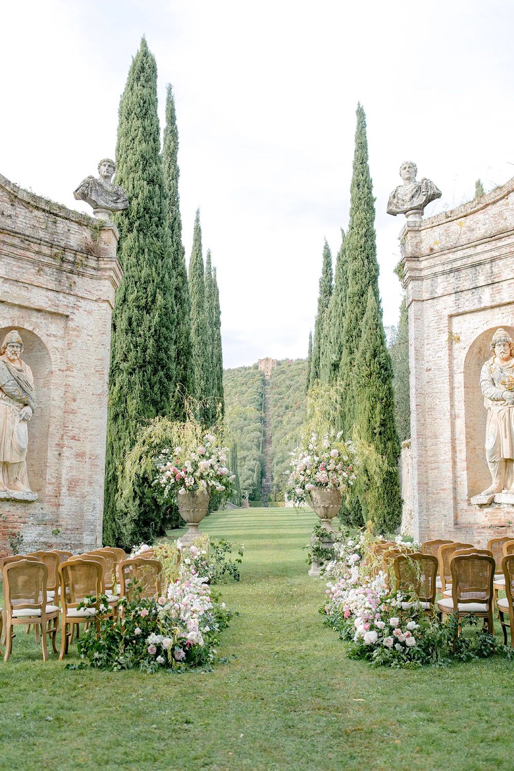 Villa Cetinale wedding ceremony: An elegant outdoor wedding ceremony at Villa Cetinale in Tuscany, Italy, framed by cypress trees, classical statues, and lush gardens in a refined editorial style.